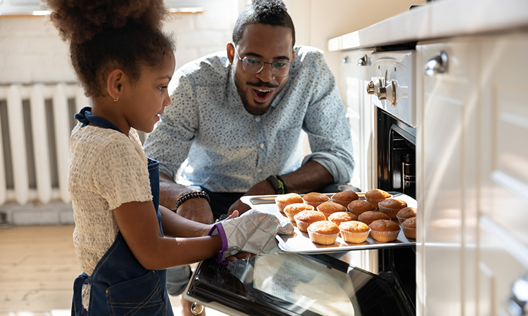 child and dad baking muffins together